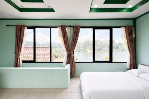 a bedroom with two beds and a large window at Cozzy Malakai Guesthouse in Palayangan