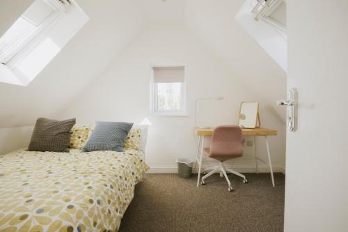 a bedroom with a bed and a desk and a chair at Coach House in Milton Keynes