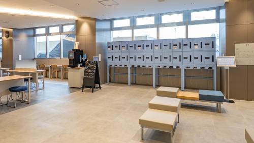 a waiting room with chairs and tables and windows at Toyoko Inn Kitakami-eki Nishi-guchi in Kitakami