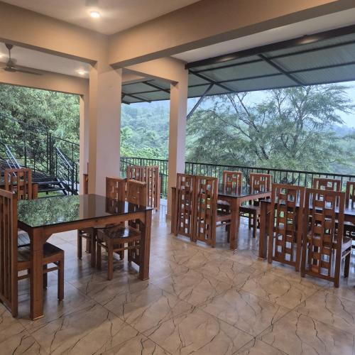 a dining room with tables and chairs and a balcony at Windowind Resort in Koroth