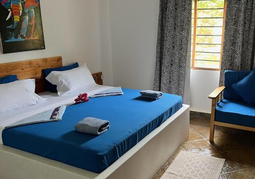 a bedroom with a bed with blue sheets and a chair at Villa Rita in Gede