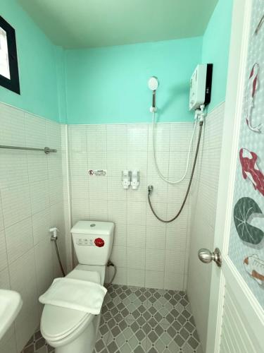 a bathroom with a white toilet and a shower at BAN SUAN KRATOM CAFE AND RESORT in Nakhon Pathom