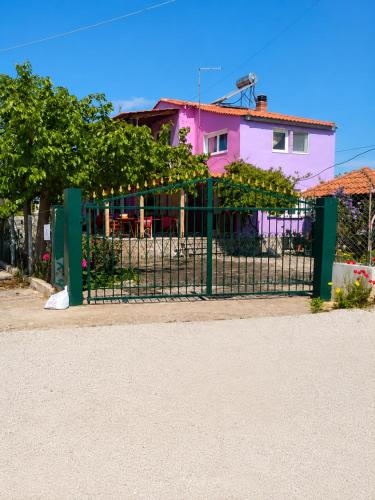 a fence in front of a pink house at Julia Country Home 200m from the Beach in Nea Plagia