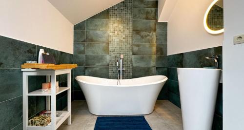a bath tub in a bathroom with green tiles at Elegant Garden Villa American Village Pipera in Voluntari