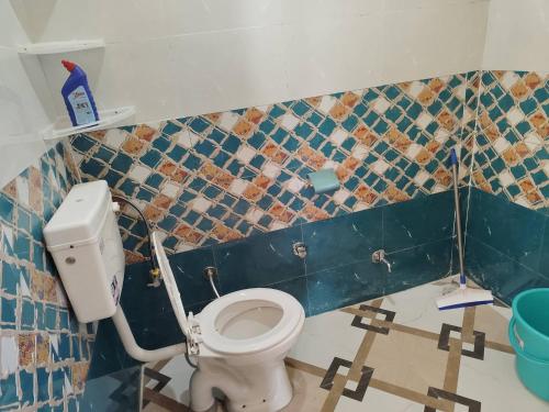 a bathroom with a toilet and a blue tiled wall at Peak Paradise homestay in Sainj