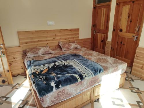 a bedroom with a large bed with a blanket on it at Peak Paradise homestay in Sainj