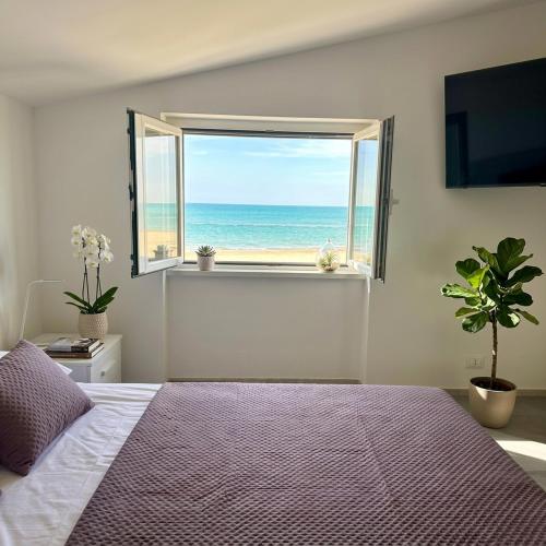 a bedroom with a large window with a view of the ocean at Fiorucci Apartments - Marco's House in Focene