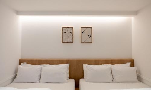 two pieces of art above a bed with white pillows at Chuncheon Bom Stay in Chuncheon