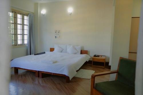 a bedroom with a white bed and a green chair at Aijal Club in Āīzawl