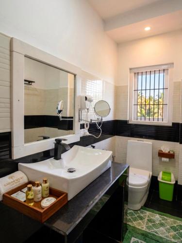 a bathroom with a white sink and a toilet at Sunshine Resort Sigiriya in Sigiriya