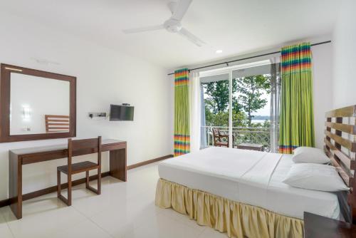 a bedroom with a bed and a desk and a window at Lavendish Wild Safari in Wasgamuwa