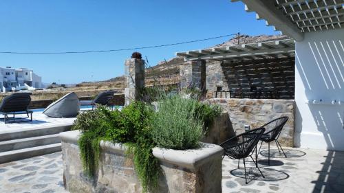 a patio with chairs and plants in a stone planter at Ventus Studios in Ano Mera