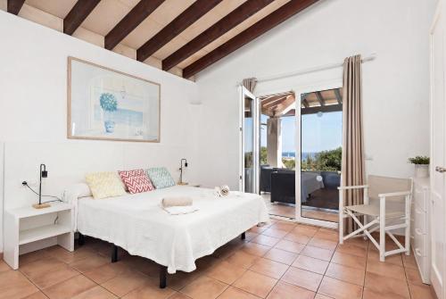 a bedroom with a bed and a chair and a window at Villa Ribes by Escape Home in Binibeca