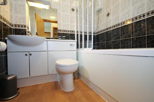 a bathroom with a toilet and a sink and a bath tub at Llety Ceiro Guesthouse in Aberystwyth