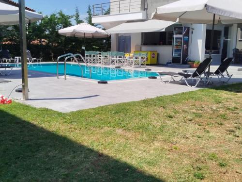a swimming pool with chairs and umbrellas in a yard at Heraclea Luxury Suites in Nea Irakleia