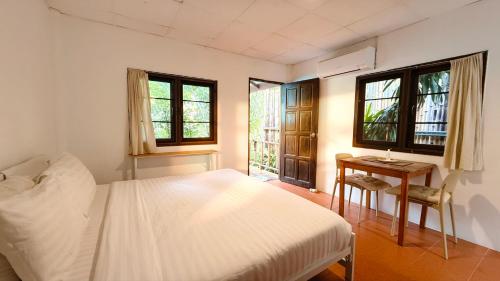a bedroom with a bed and a table and windows at Zen Hideaway - Cute Modern Thai Home in Ko Phangan