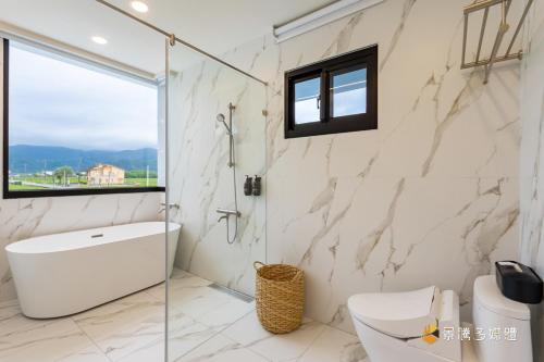 a bathroom with a shower and a toilet and a sink at 亮Villa in Sanxing