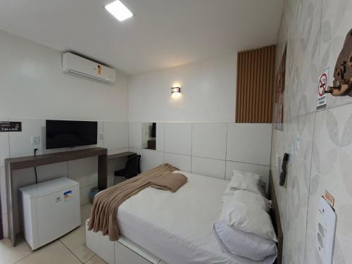 a small bedroom with a bed and a television at Pousada Rota do Pilão in Araçoiaba