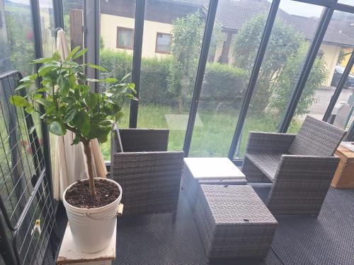 a balcony with three chairs and a potted plant at Ernies Gartentraum in Mattsee