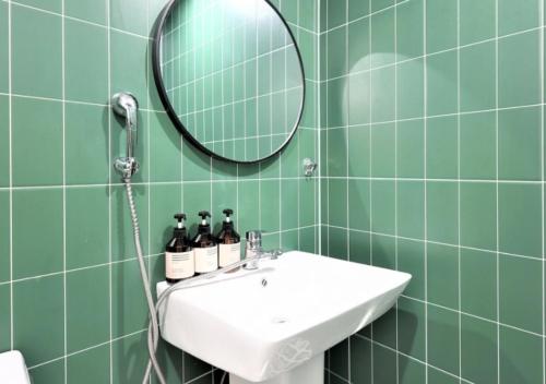 a green tiled bathroom with a sink and a mirror at From H Dongbaek Hotel by Kwon Gohyeon in Geoje