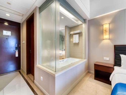 a bathroom with a tub and a bed in a room at 杭州海外海纳川酒店 in Hangzhou