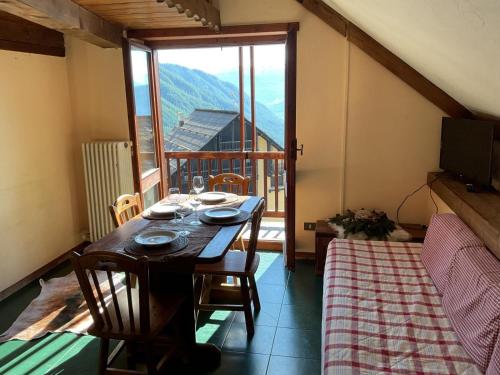 ein Esszimmer mit einem Tisch und einem großen Fenster in der Unterkunft Sestriere-Sises Lodges, Appartamenti Moderni, vicino alle piste in Sestriere
