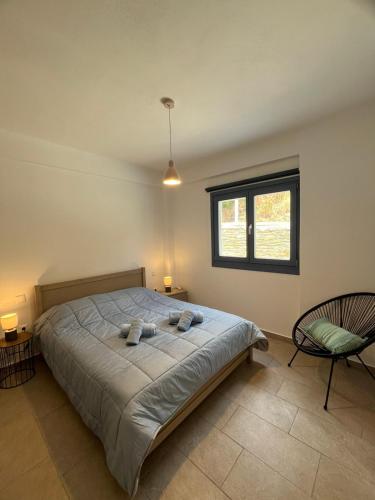 a bedroom with a bed and a chair and a window at Aegean Mirror Andros in Apróvaton