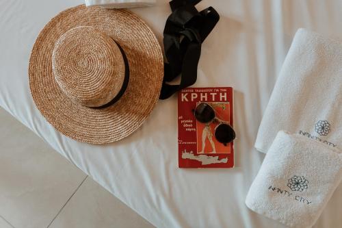 a hat and a book on a bed with a towel at Infinity City Boutique Hotel in Heraklio