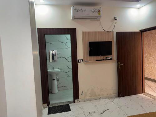 a bathroom with a toilet and a tv and a door at Kailashi Hotel Har ki pauri in Haridwār
