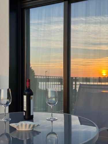 a glass table with a bottle of wine and two glasses at Apartamentos turísticos El Pinar in Mogro