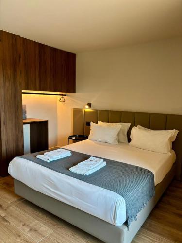 a bedroom with a large bed with two towels on it at Vila Hotel By VimaHotels in Guimarães