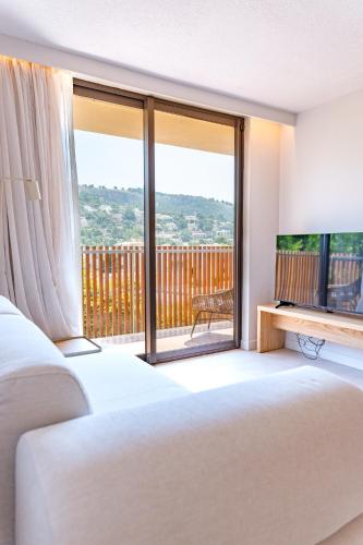 a bedroom with a bed and a television and a balcony at Canyamel Sun Suites Hotel in Canyamel