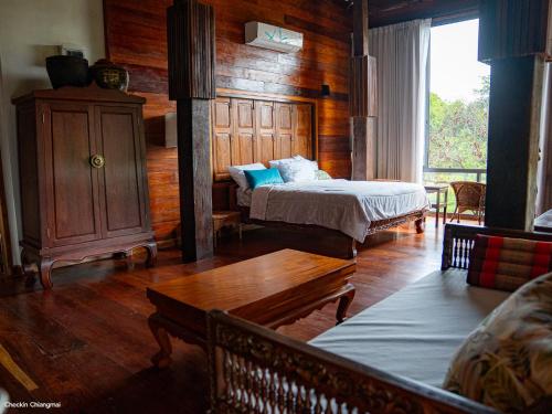 a bedroom with two beds and a wooden wall at บ้านริมดอย แม่ริม in Ban Mae Raem
