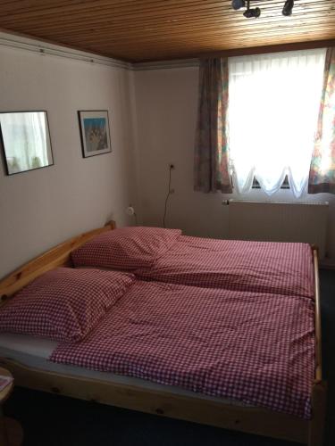 a bedroom with a bed with a red checkered blanket at Haus Petra in Sonnenalpe Nassfeld