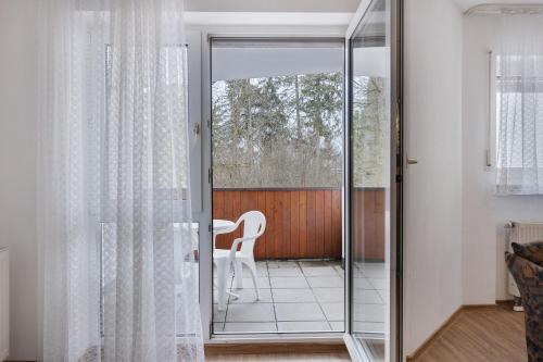 a glass door leading into a living room with a chair at Parkblick Doppelzimmer 26, 29 in Bad Dürrheim