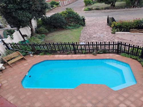 a blue swimming pool with a fence around it at A1Bay View Guest House Cottage & Apartment SEA FACING in Jeffreys Bay