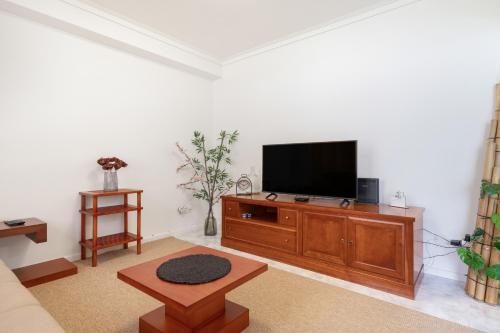 a living room with a flat screen tv on a wooden entertainment center at On the Beach at Amorosa in Viana do Castelo