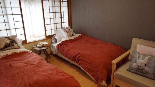 a bedroom with two beds and a chair and windows at Rabbit Island Inn in Mihara