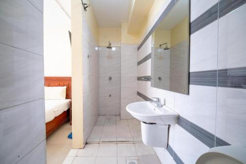 a bathroom with a sink and a toilet and a bed at Capital comfort Hotel Ambala Rd in Nairobi