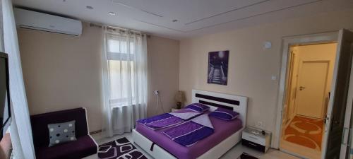 a bedroom with a purple bed and a chair at AMY APARTMAN in Tuzla