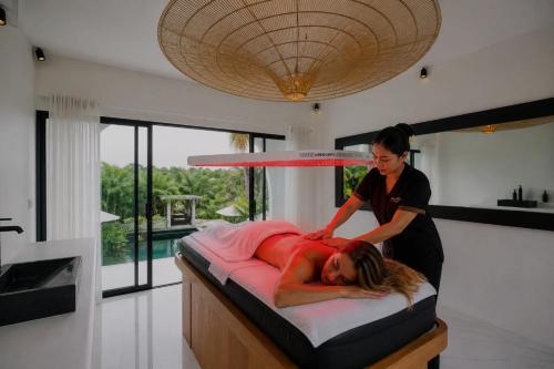 a woman laying on a bed in a room at White Palm Uluwatu - Wellness & Recovery Retreat - 2 Min Walk to Balangan Beach in Jimbaran