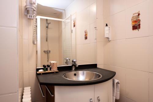 a bathroom with a sink and a mirror at Logis Hotel les Sapins in Le Ménil