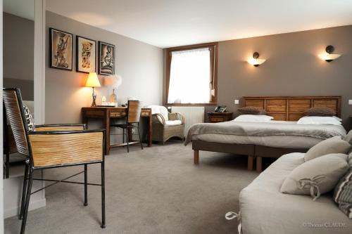 a bedroom with two beds and a desk and a chair at Logis Hotel les Sapins in Le Ménil