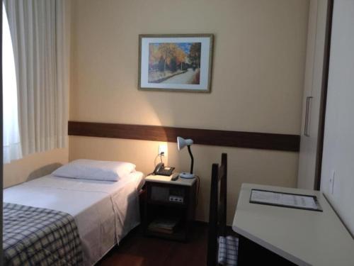 a hotel room with a bed and a phone on a table at Hotel São Bento in Belo Horizonte