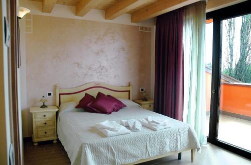 a bedroom with a bed with purple pillows and a window at Agriturismo Aver in Villafranca di Verona