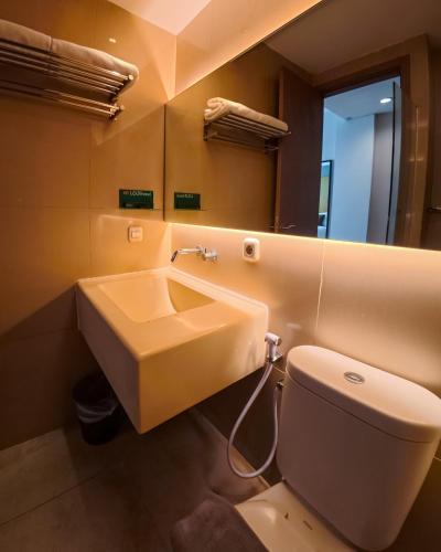 ein Badezimmer mit Waschbecken, Toilette und Spiegel in der Unterkunft Loji Hotel in Solo