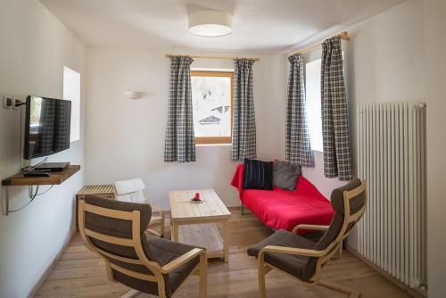 a living room with a red couch and a table at Casa Alfredino in Rocca Pietore