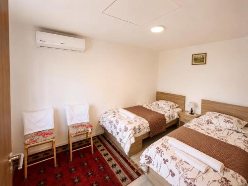 a room with two beds and two chairs at Garden Guesthouse in Gjakove