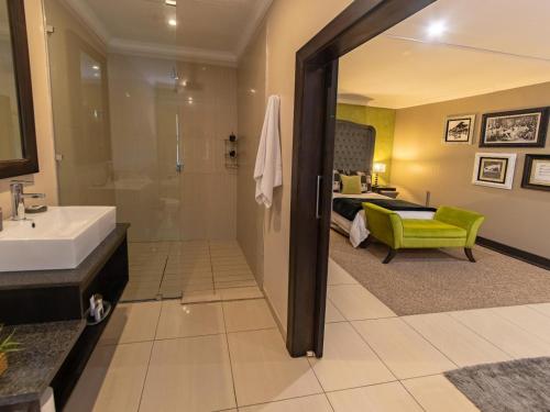a bathroom with a sink and a shower and a bedroom at Altissimo Guesthouse in Bloemfontein