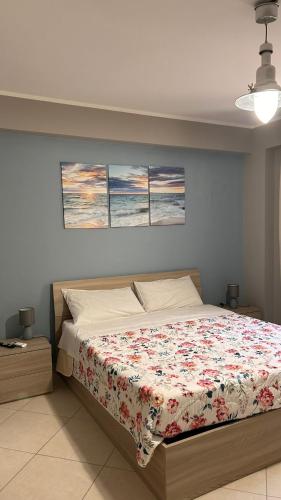 a bedroom with a bed with three paintings on the wall at La camera a Lido Burrone in Favignana